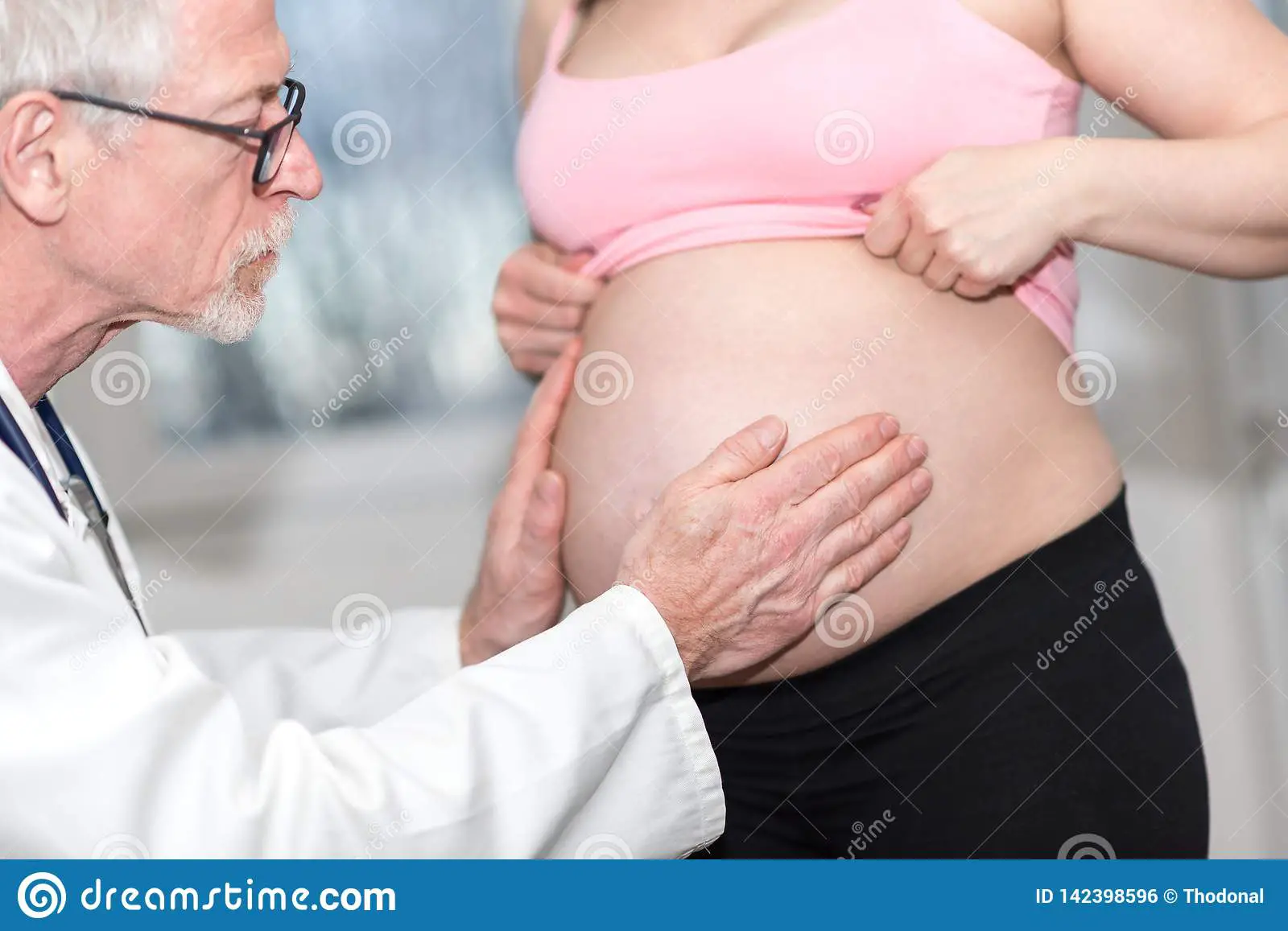 Doctor Examining Belly Of Pregnant Woman Stock Photo